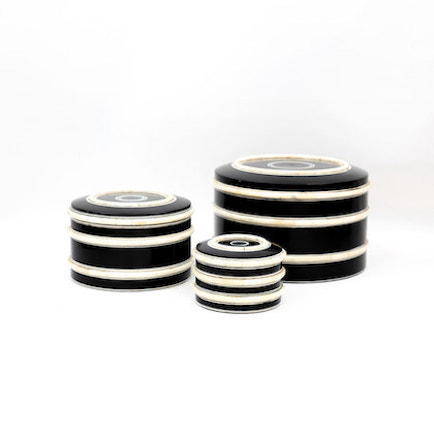 Round, black box with horizontal white stripes displayed on a shelf. Three available sizes shown.