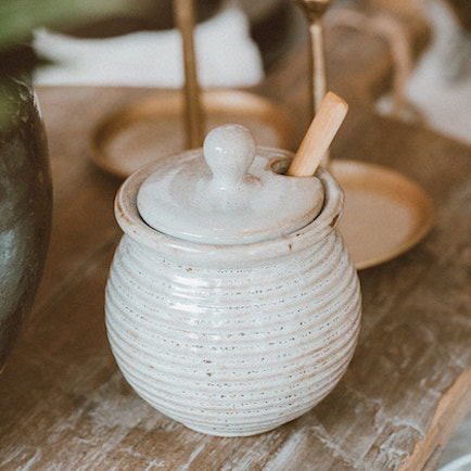 Honey pot, with milky white glaze finish displayed on a kitchen table