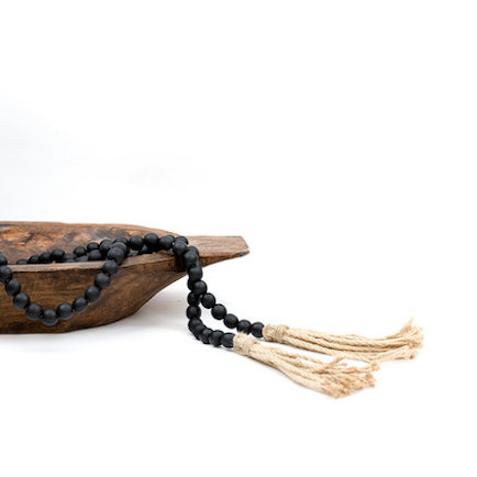 Black wooden beads with Natural jute tassels displayed in a wooden bowl