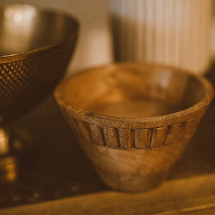 Hand-carved small dip bowl made from mango wood sitting on shelf