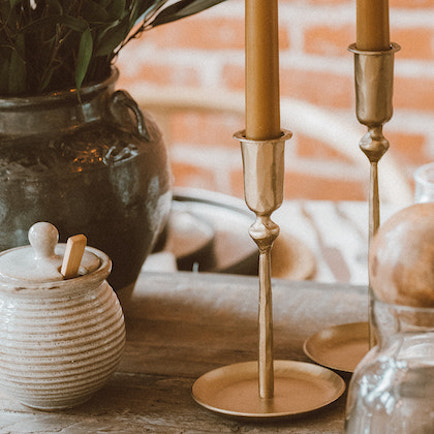 Brass, taper candlestick holder. Available in two sizes. Shown on a dining table