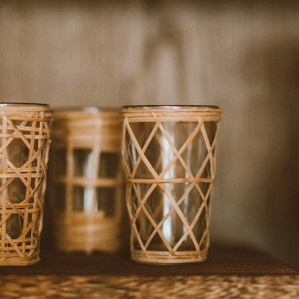 A group of three recycled glassware, sheathed in interlaced rattan.